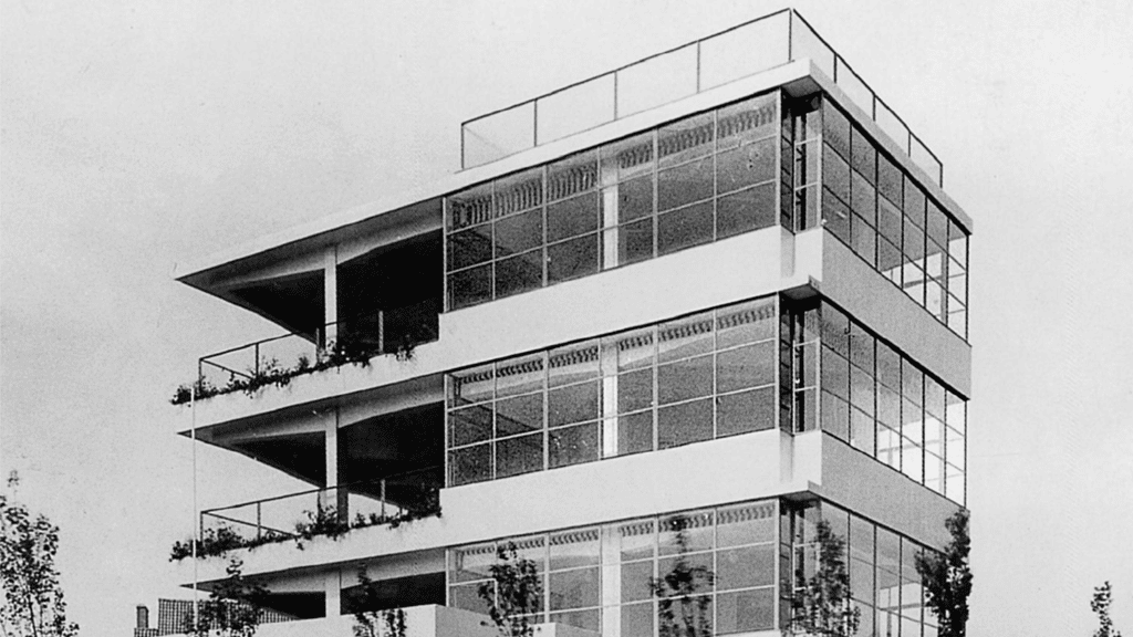 Black and white photograph of open air school building with high glass windows and open terraces. 