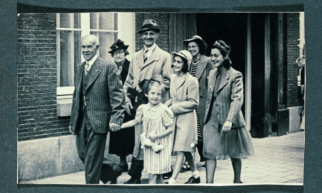 Otto Frank smiling at camera walking down the street with family. 
